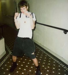 a young man holding a baseball bat in his right hand while standing on a tiled floor