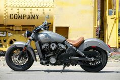 a gray motorcycle parked next to a yellow train car in front of a construction site