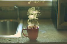 a steaming cup of coffee sitting on top of a counter