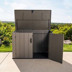 an open storage box sitting on top of a cement floor next to a lush green field