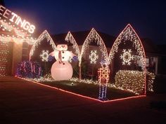 christmas lights decorate houses and trees with snowmen on the front yard, along with an inflatable snowman