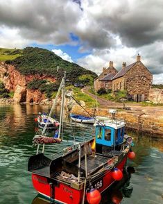 two boats in the water next to a house and some hills with houses on them