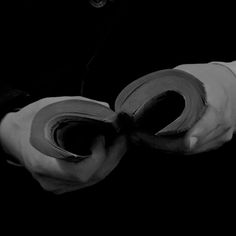 a pair of white gloves holding rolled up toilet paper in the dark with one hand