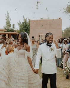 a man and woman are walking down the aisle with confetti thrown in the air