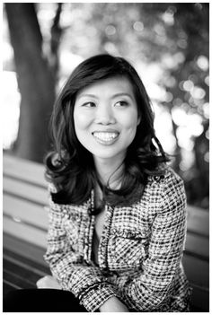 a woman sitting on a green bench in front of a tree and smiling at the camera