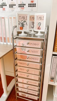 a pink dresser with white drawers and numbers on the top, next to a wooden table