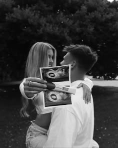 black and white photograph of a man holding an open photo album with a woman looking at it