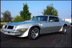 a silver muscle car parked in a parking lot