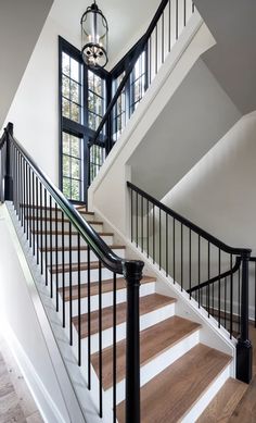 a white staircase with black handrails leading to a second story window and door