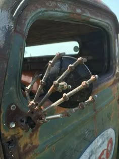 an old green truck with rusted parts in the cab