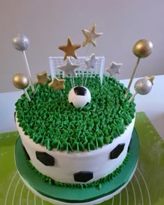 a soccer themed birthday cake with green frosting and gold stars on top, sitting on a table