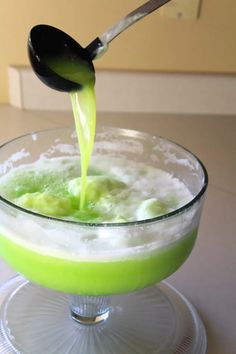 a spoon pouring green liquid into a bowl