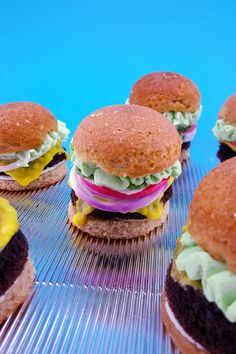 several hamburgers with different toppings on top of a cooling rack in front of a blue background