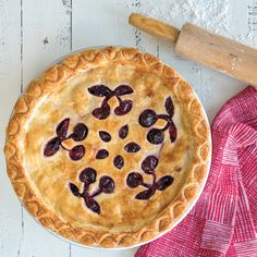 a pie sitting on top of a white table next to a red napkin and wooden spatula