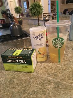 starbucks drinks are sitting on the counter next to a box of green tea and a carton of orange juice