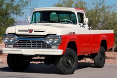 an old red and white truck parked on the street