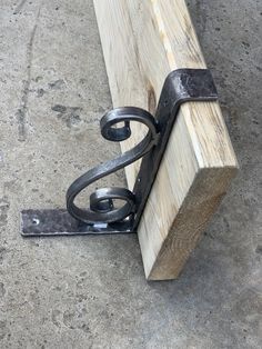 a wooden bench sitting on top of a cement floor next to a metal hook and chain