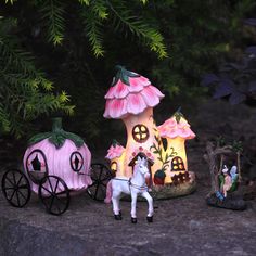 three fairy figurines are sitting on the ground next to a horse and carriage