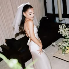 a woman in a white wedding dress standing next to a table with flowers on it