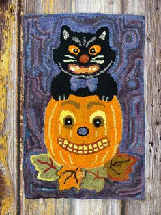 a black cat sitting on top of a jack - o'- lantern with an orange pumpkin