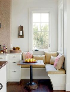 a window seat in a kitchen with fruit on the table and other items around it