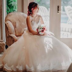 a woman in a wedding dress sitting on a chair