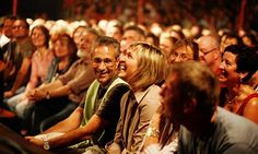 a group of people sitting next to each other in front of a crowd with their eyes closed