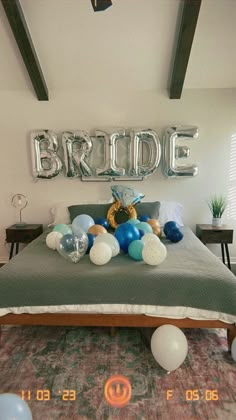 a bed with balloons on it and the word bride spelled out in large silver letters