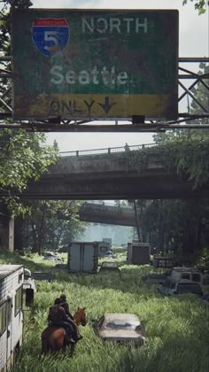 two people sitting in the grass under an overpass