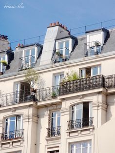 an apartment building with balconies and plants on the balconies, against a blue sky