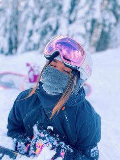 a woman sitting in the snow with her skis and goggles over her face