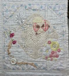 a white quilted wall hanging with an image of a sheep and flowers on it