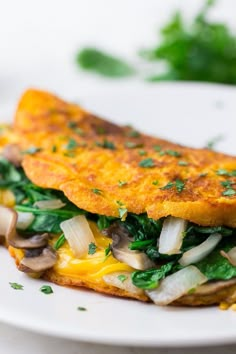 an omelet with spinach, mushrooms and cheese on a white plate next to parsley