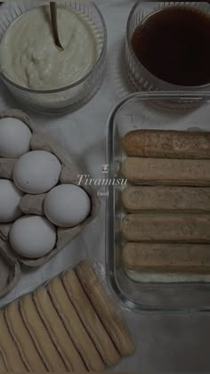 an assortment of food including eggs, bread and other items on a white table cloth