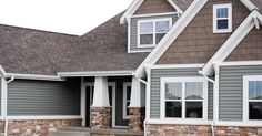 a house with gray siding and white trim on the windows, grass in front of it