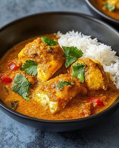 two black bowls filled with curry and white rice