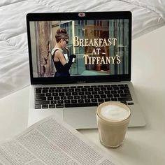 an open laptop computer sitting on top of a desk next to a cup of coffee