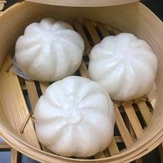 three dumplings are sitting in a bamboo steamer