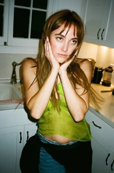 a woman standing in a kitchen with her hands on her face