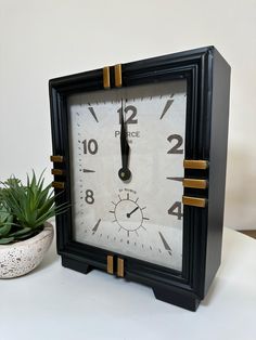 a black and white clock sitting next to a potted plant