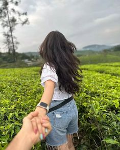 a woman holding the hand of a man in a field