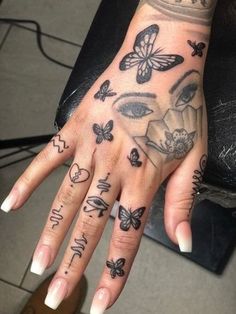 a woman's hand with tattoos on it and butterflies flying around her fingers,