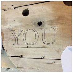 a piece of wood with the word you written on it and two holes in the side