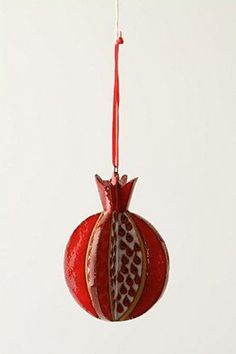 a red and white ornament hanging from a string in the shape of a pomegranate