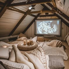 Cozy attic home cinema with pillows, blankets, and candles, perfect for movie nights in a rustic setting. Home Cinema Attic, Movie Room Attic, Cinema Attic Room, Attic Bedroom Ceiling Ideas, Attic Home Theater, Cosy Attic Room, Cosy Cinema Room, Cosy Attic Bedroom, Attic Tv Room Sloped Ceiling