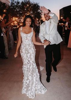 a man and woman holding hands while walking down the dance floor