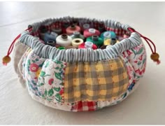 a close up of a bag filled with different colored thread and spools on a white surface