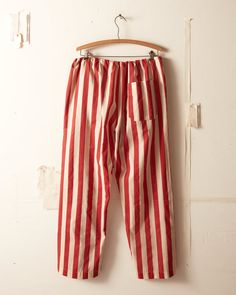 These pants are inspired by a 1940s curtain valance. The original stripe has been replicated by rotary printing, a process which pushes ink through the fabric rather than stamping it on one side. The pearl buttons used on this piece were sourced from a now-defunct factory in Iowa which had been making buttons for over Making Buttons, Striped Pajamas, Striped Pajama Pants, Curtain Valance, Hand Logo, Striped Pyjamas, Bed Linens, Pajama Pant, How To Make Buttons