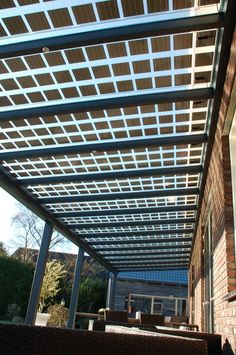 an outdoor covered patio with chairs and tables under a pergolated roof over looking the yard