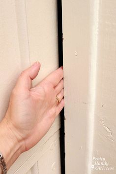 a person's hand is holding on to the side of a white door handle